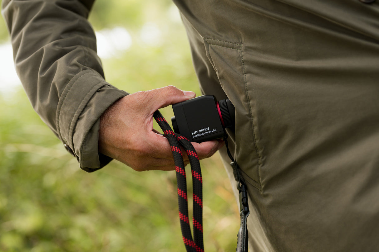 Hand pulling compact Kite Stabi One from jacket pocket, showing pocket-sized form factor with neoprene strap