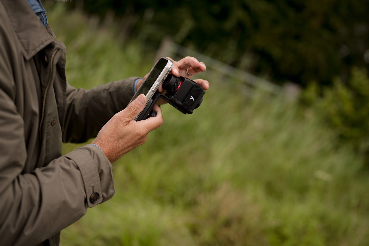 Close-up of hands attaching smartphone to Kite Stabi One phone mount adapter outdoors
