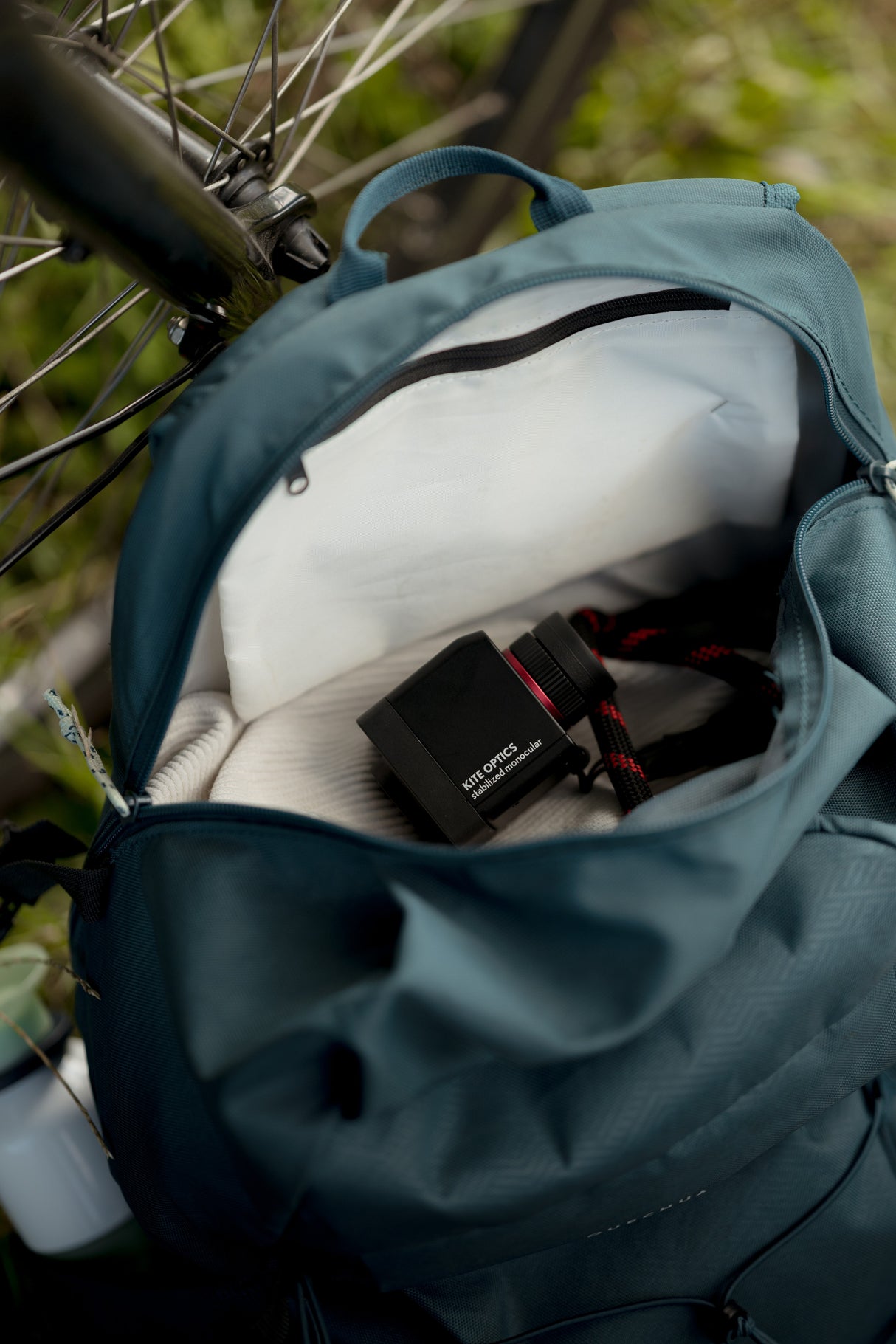 Kite Stabi One with neoprene strap tucked inside open cycling backpack next to bicycle