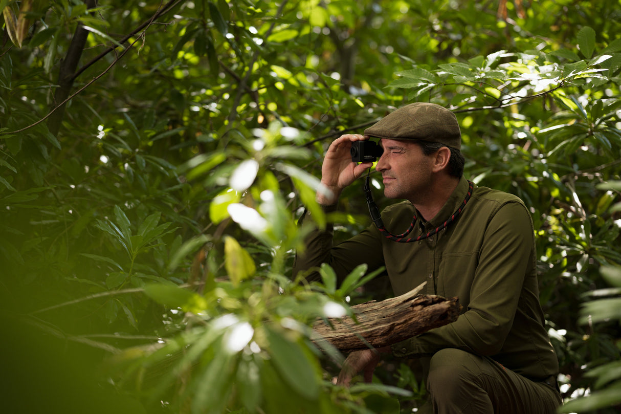 Hunter using Kite Stabi One as monocular while seated in dense green foliage