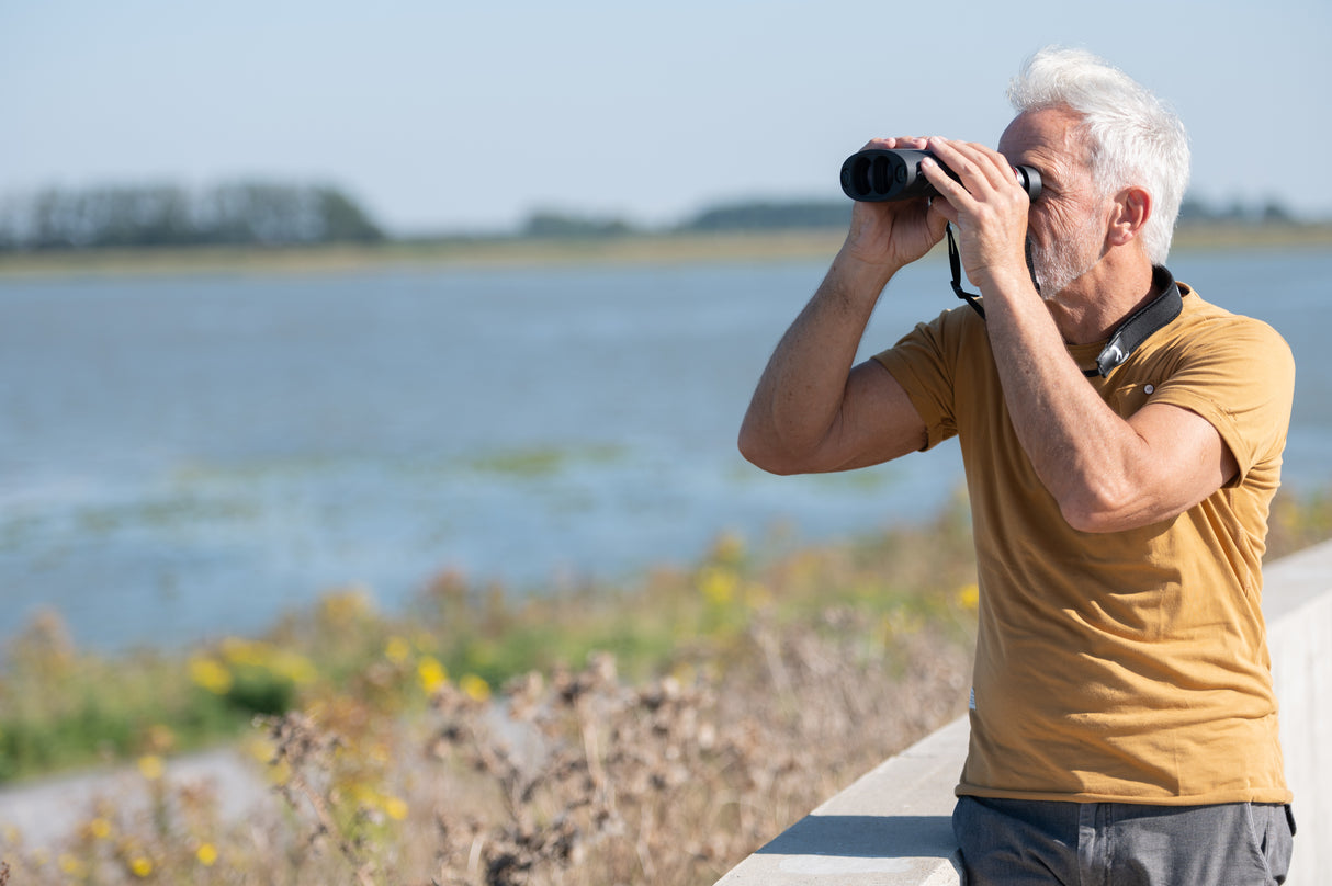 Man using Kite Optics APC 42 stabilized binoculars for seawatching along a coastal waterway