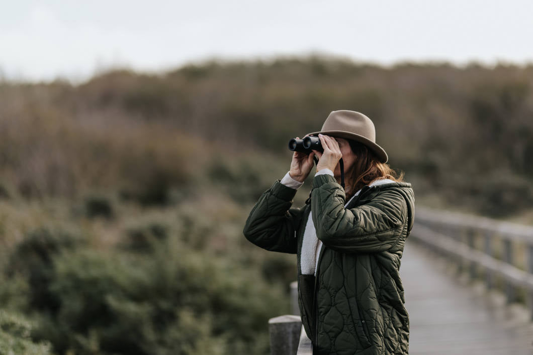 Birder using Kite Optics binoculars on a nature reserve boardwalk