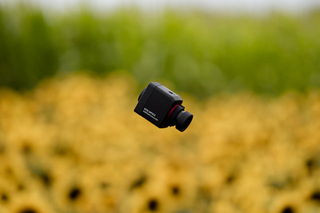 Kite Stabi One suspended in air against sunflower field bokeh, showing compact cube design
