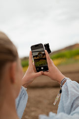 Over-shoulder view of woman digiscoping with Kite Stabi One, phone screen showing magnified distant sign