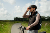 Cyclist looking through Kite Stabi One as monocular while standing with bicycle on country path
