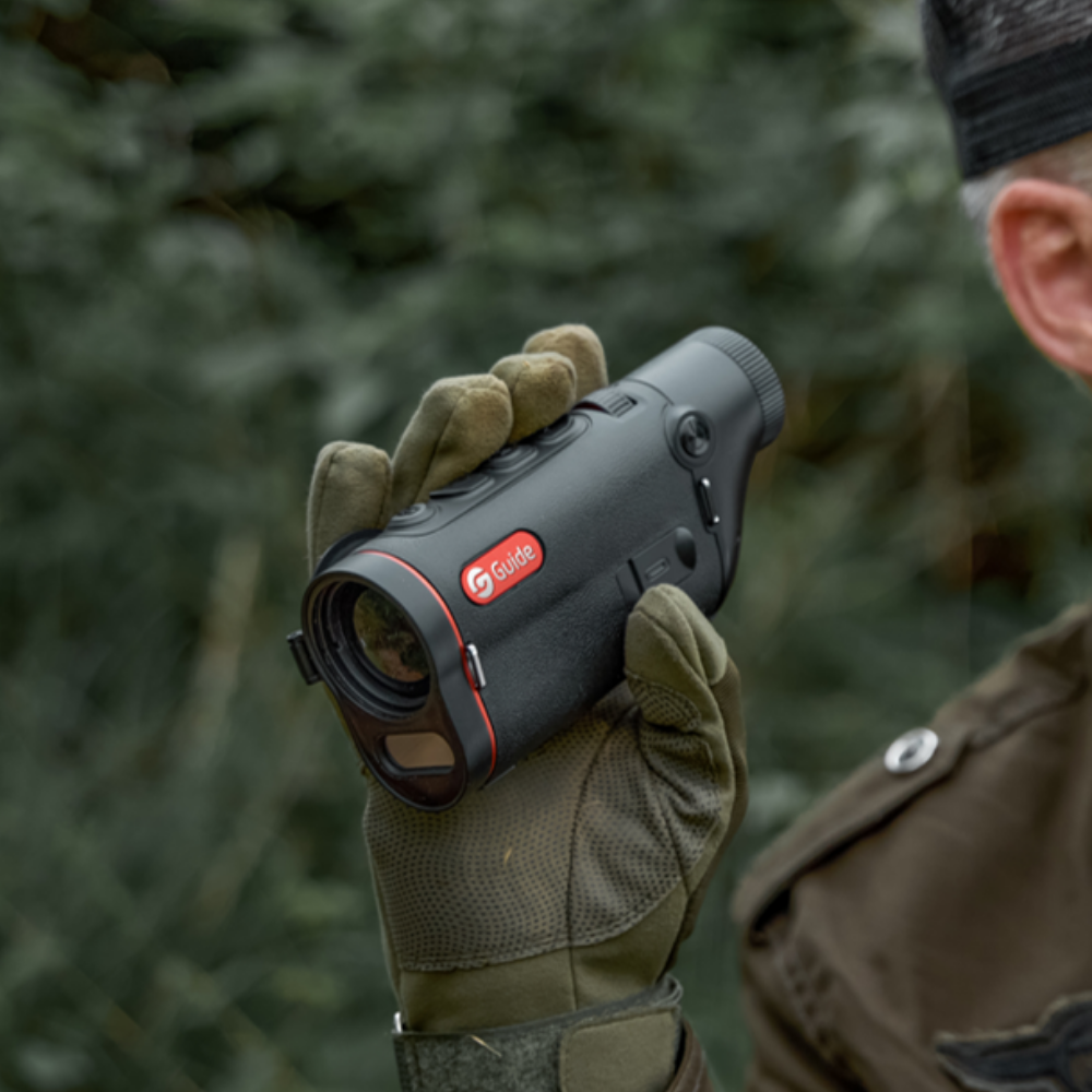 Guide TD 633L thermal monocular held in gloved hand in the field, showing ultra-compact pocketable size